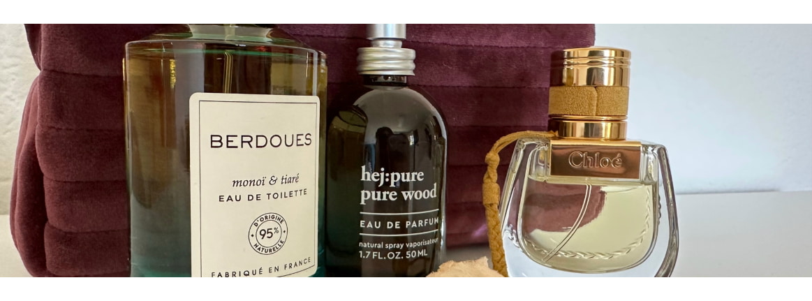 trois flacons de parfum sur une table avec une trousse de maquillage