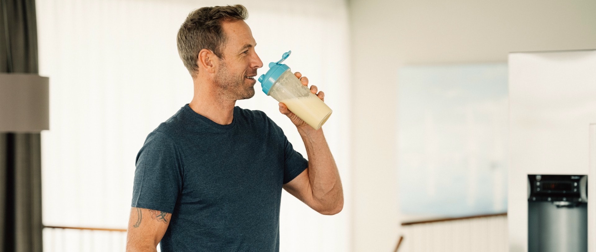 Un homme boit un shake proteine dans la cuisine
