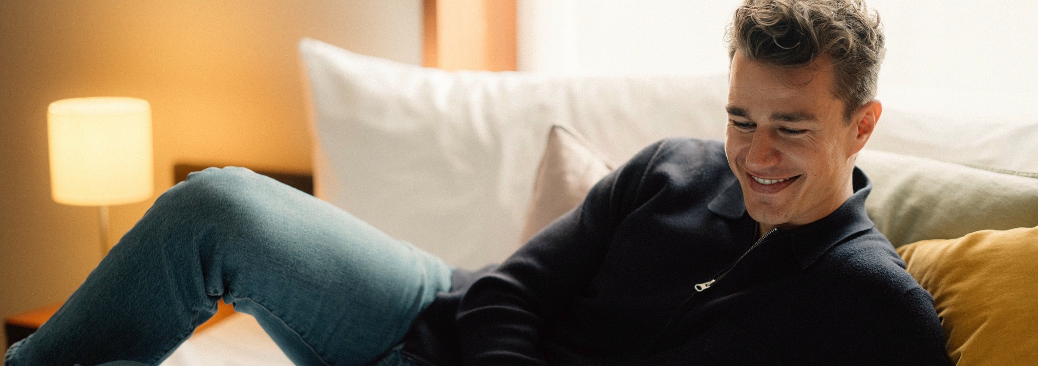 mann liegt zwischen kissen auf sofa