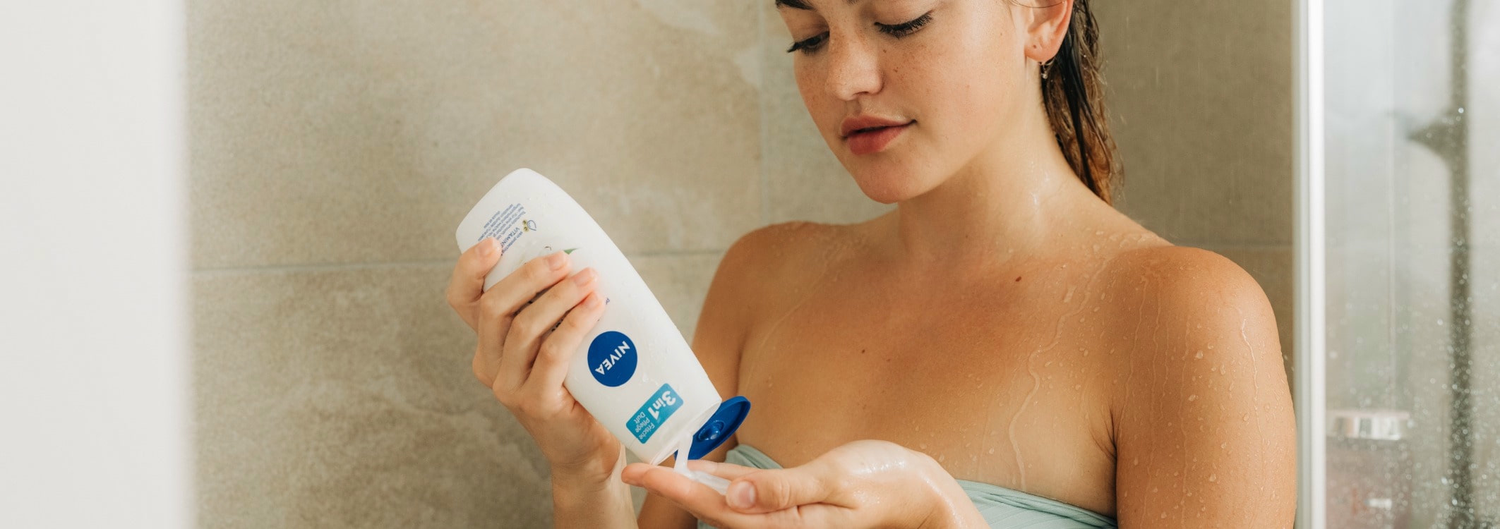 femme qui met du gel douche dans la douche sur sa main